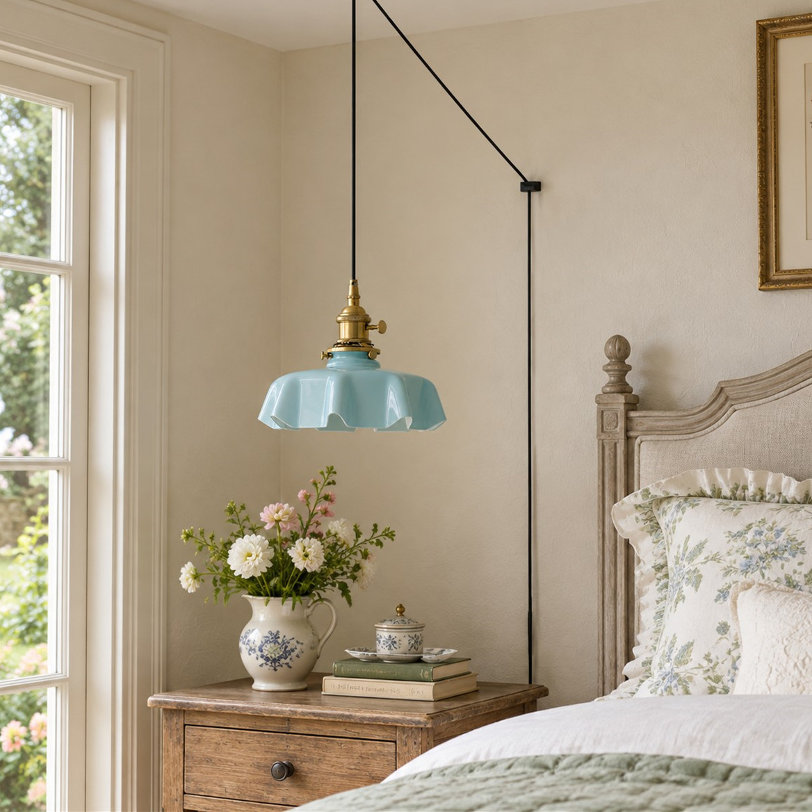 Lámpara colgante de cristal con forma de flor amarilla junto a una cama de estilo suave.