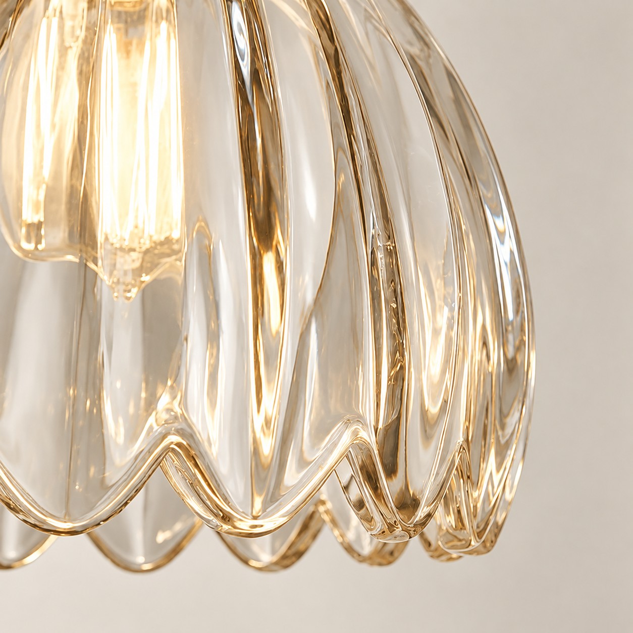 Close-up of the curved glass petals and scalloped edge around a glowing bulb