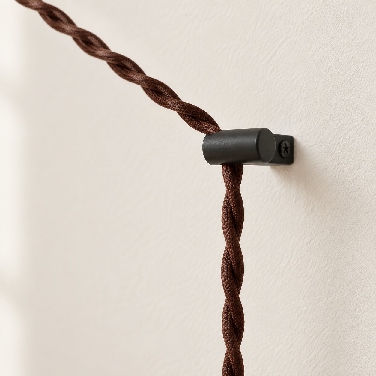 Close-up of the brown braided cord held by a black wall hook
