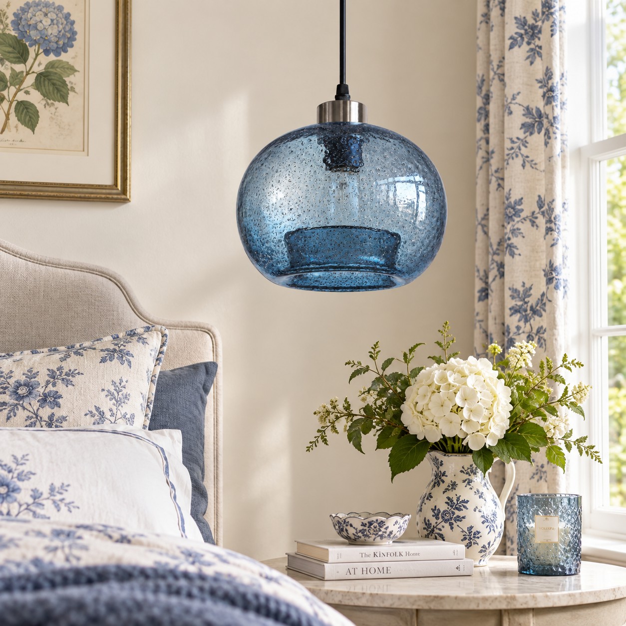 Lámpara colgante de globo de cristal azul texturizado sobre una mesita de noche en un dormitorio con decoración floral.