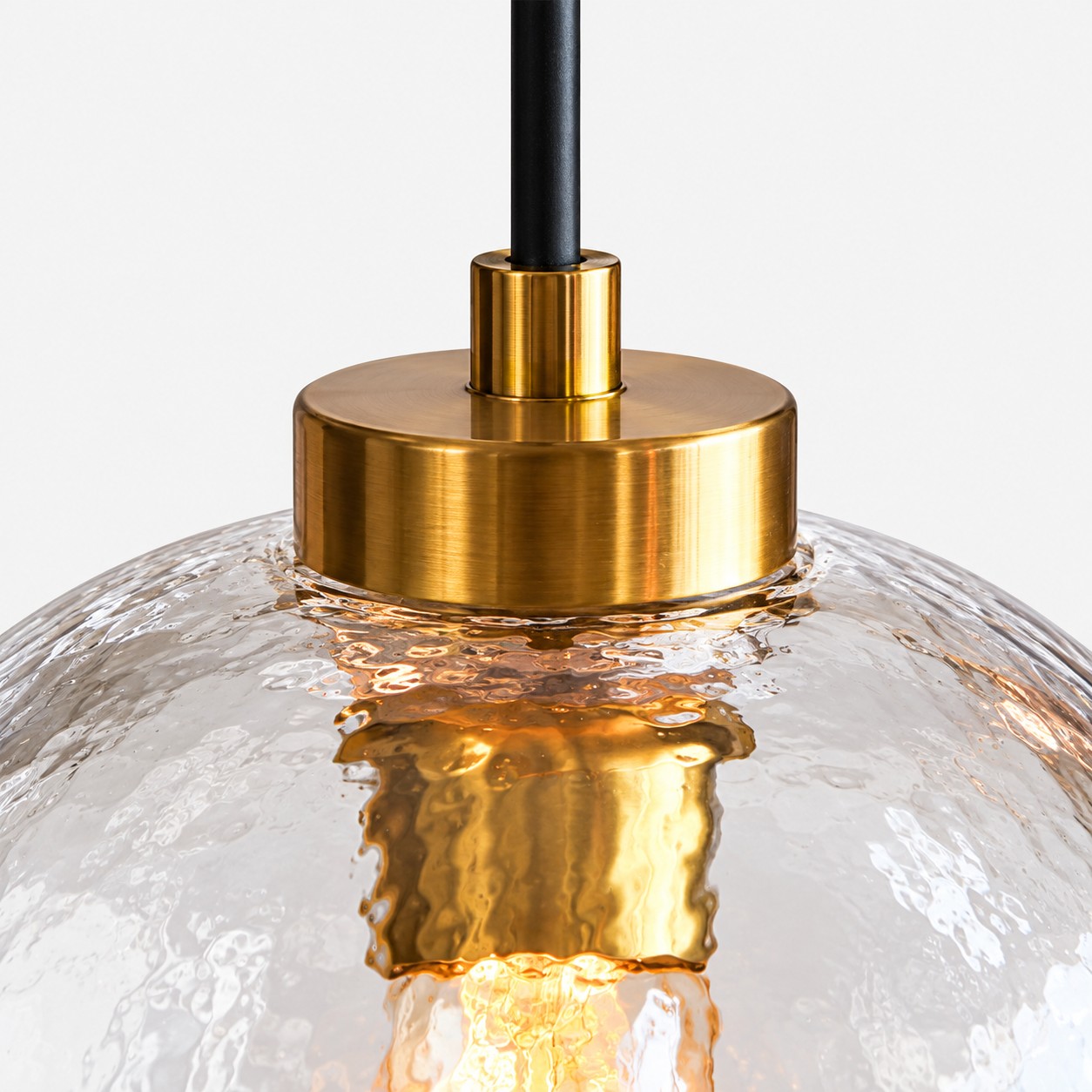 Pantalla y portalámparas de metal color dorado sobre cristal transparente texturizado.